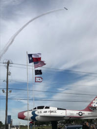 Jet contrail overhead, F-84F and flags below